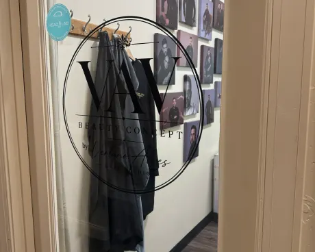 A black cape hanging under the studio sign, by the wall of portraits