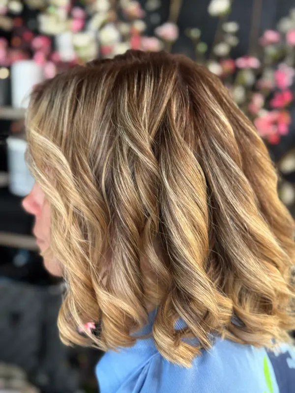 Honey balayage on a bob, set in loose waves and seen from the side