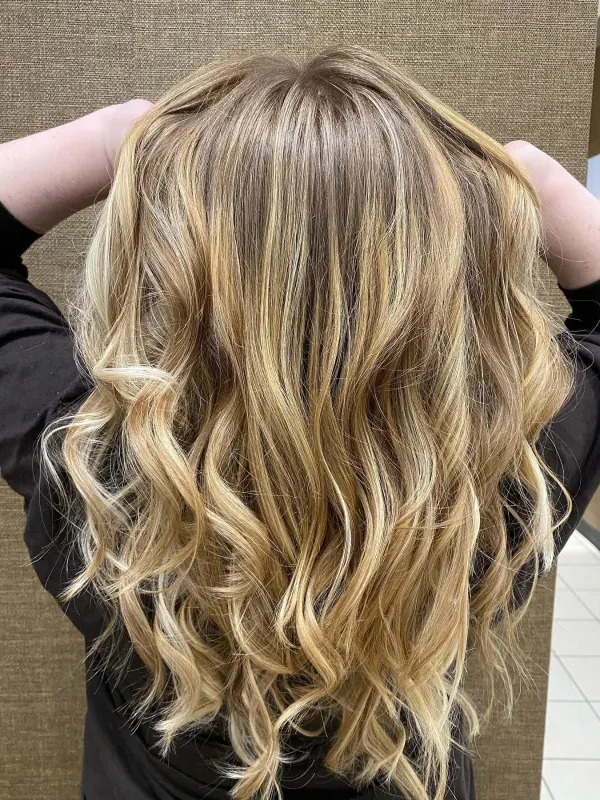 Honey blonde worked through long hair and set in loose waves, seen from behind