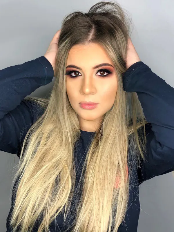 Long blonde over a deliberately deep root, worn straight down the back