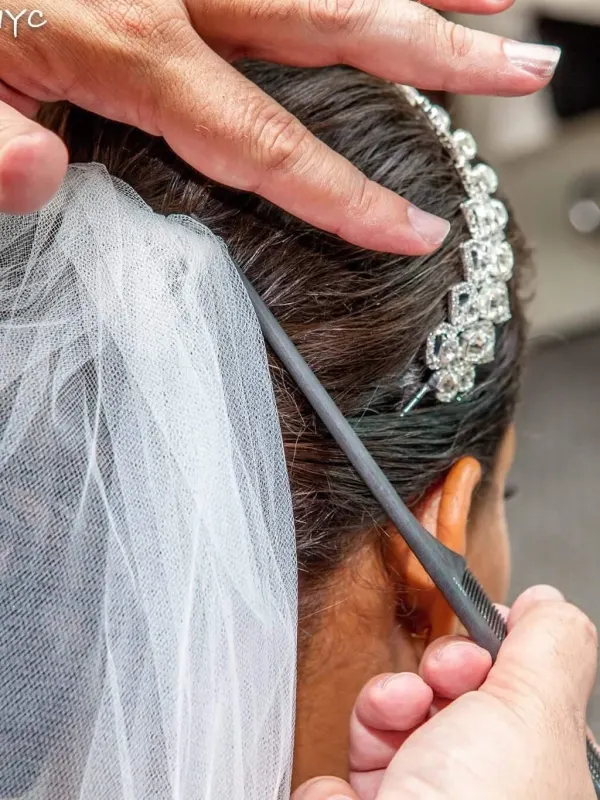 A crystal comb and veil being set into a bridal updo