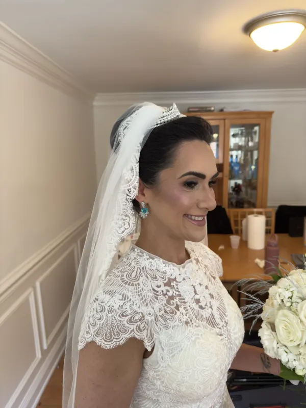 Bridal hair pinned back under a lace veil, set to hold all day